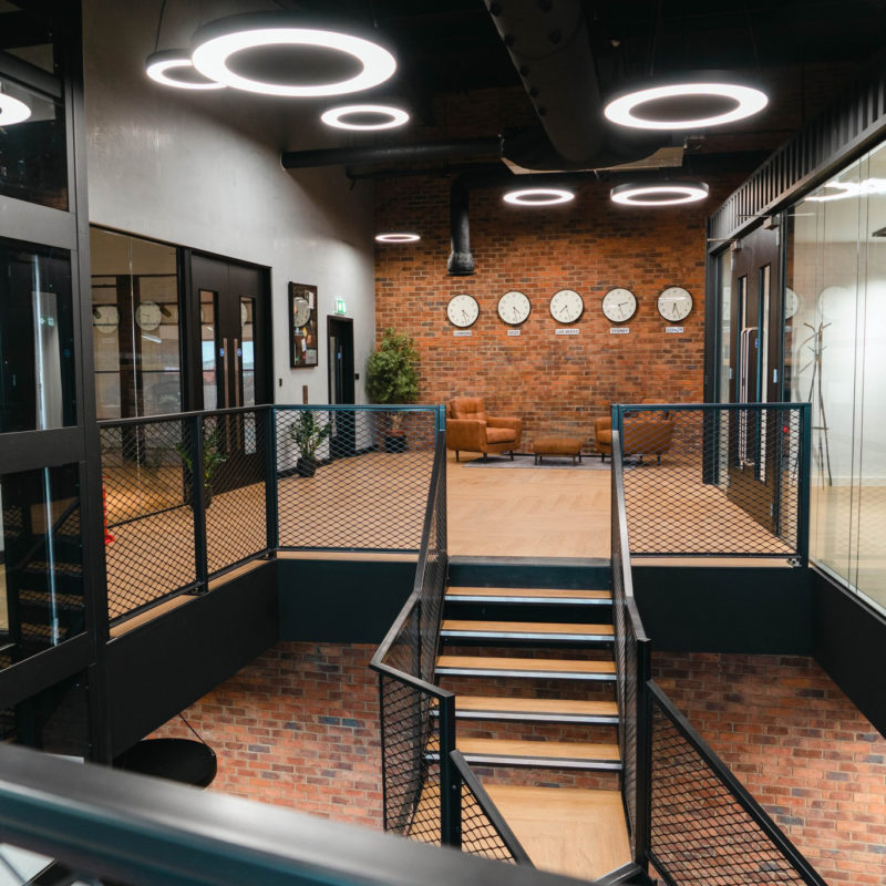 Office Fit out with mezzanine and shipping container details. Glass and black lift and circular pendant lighting